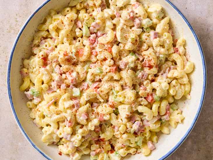 Creamy macaroni salad with elbow pasta, diced ham, celery, and bell pepper, topped with paprika.